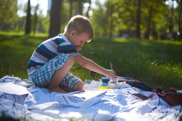 a boy of five to six years old draws in nature