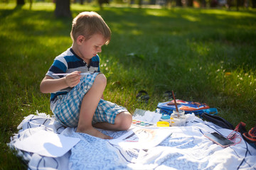 a boy of five to six years old draws in nature