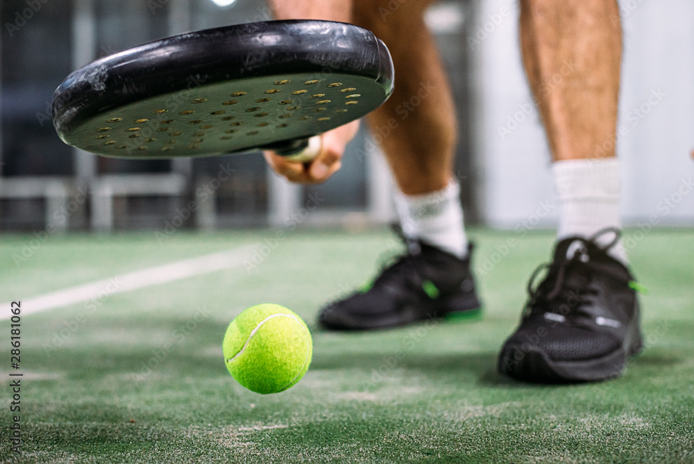 Wall mural Crop man taking padel ball from ground