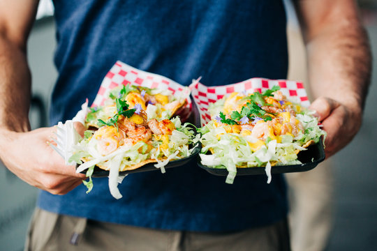 Man holding mesquite smoked shrimp tacos, street food