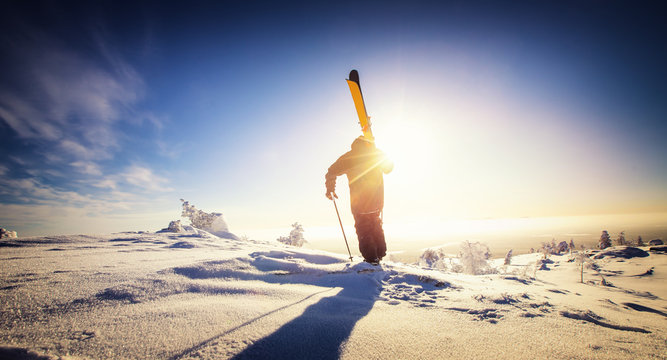 Skier stand mountain top with ski in hands. Winter extreme freeride concept