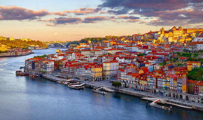 Fototapeta na wymiar Antique town Porto, Portugal. Sunset sun over silhouettes skyline of roofs of houses along river.