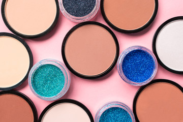 Makeup cosmetics. Beautiful colorful eyeshadow on a pink background. Beauty products. Round shape. Close up. The view from the top, flat lay. Multicolored shimmer. Beige color eye shadow.