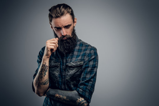 Bearded skinny man with tattooes feels dispair and sorrow while thinking about life.