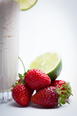 lime and ripe strawberries on a cocktail against white background