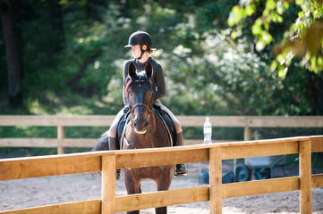 Young pretty girl resting after horse riding training on arena