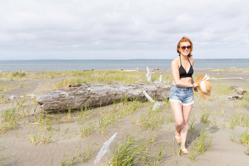 Pretty woman with red hair and denim shorts at beach