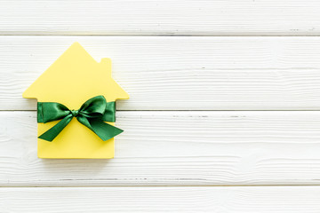 Buying a new house concept with house figure on white wooden background top view space for text