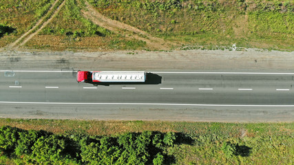 Truck on a highway road between fields view from drone