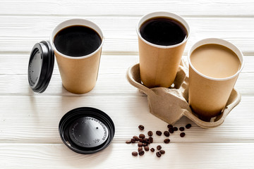 Caution: contents hot. Coffee to take away in paper cups with lids and beans on white wooden table background