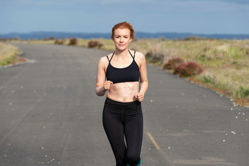 Pretty woman with red hair exercising outside