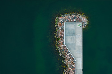 Aerial view of the calm sea and the stone pier with wave breaker.