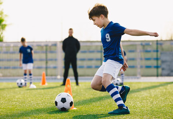 Children training football dribbling in a field. Kids Running the Ball. Players develop soccer...