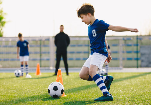 Children training football dribbling in a field. Kids Running the Ball. Players develop soccer dribbling skills. Boys training with balls and cones. Soccer slalom drills