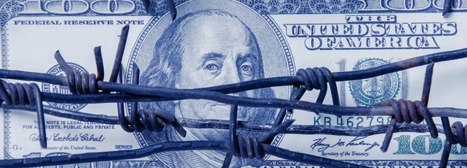 Economic warfare, sanctions and embargo busting concept. One hundred US Dollar bill wrapped in...