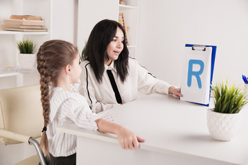 Child with therapist working on pronunciation and sounds together sitting in the class
