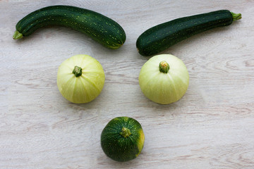 Funny still life of vegetables on wooden table. Zucchini, top view. Healthy vegan food.