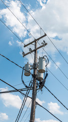 Power line pole with a transformer on it. Typical wooden post from USA