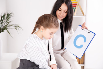 Child with therapist working on pronunciation and sounds together sitting in the class