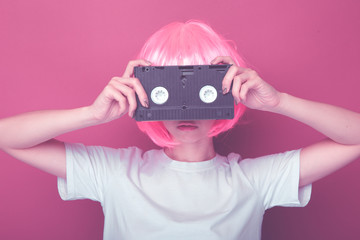 Young girl 90s and VHS cassette on pink background.