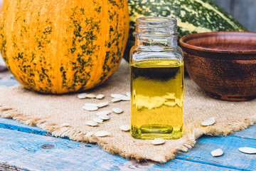 Closeup of a bottle of pumpkin seed essential oil on a napkin with burlap.