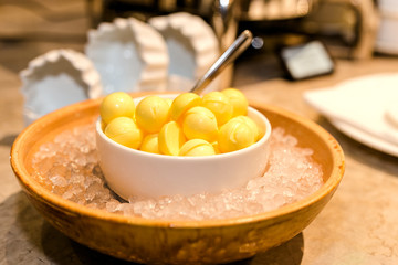 cold yellow butter in the shape of balls in white bowl, in ice