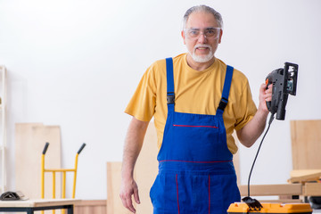 Old male carpenter working in workshop