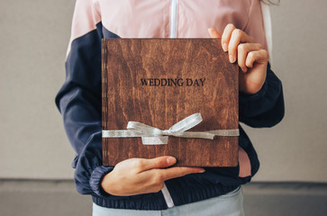 Photobook of wood. Wedding photo album with a wooden cover is is hands girl