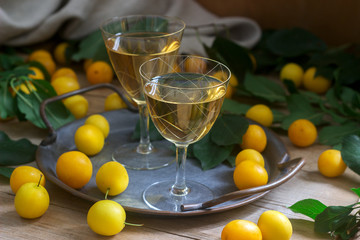 Cherry plum liqueur in small glasses and cherry plum on a wooden background. Rustic style.