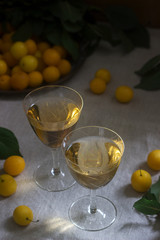 Cherry plum liqueur in small glasses and cherry plum on a wooden background. Rustic style.