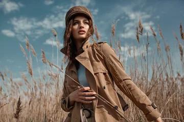 Poster Beautiful Young Stylish Girl in Trench Coat Walking Autumn or Spring street. Autumn outdoor fashion. © svitlychnaja