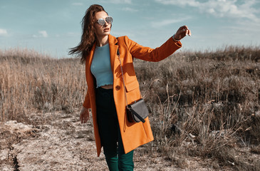 Autumn fashion. Beautiful attracrive young woman in bright autumn look. Orange trendy coat and...
