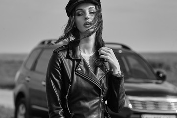 High fashion portrait of brunette woman outside in leather black jacket and trendy hat. Outdoor...