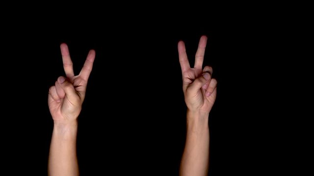 Victory or peace gesture shown with both hands on a black background by a white caucasian male.