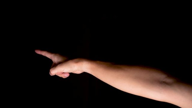 Close up view of a male's hand pointing with the forefinger to the background. He is indicating to someone the direction to follow or he is pointing to show a location.