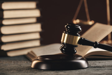 Law concept - Open law book with a wooden judges gavel on table in a courtroom or law enforcement...