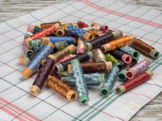 Bright thread on wooden spools, thimbles and needles