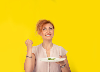 Euphoric woman pumping fist holding a white plate with salad