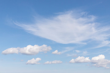 Blue sky with white clouds. In the sky you can see small fluffy white clouds. Feather clouds can also be seen. Sunny weather. Daytime weather. Background with free space and empty place.