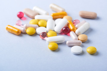 Multicolor vitamins and supplements on bright paper background. Concept for a healthy dietary supplementation. Copy space. 