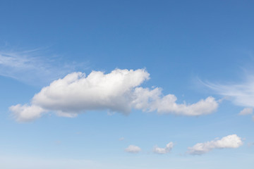 Blue sky with white clouds. A small cloud on the blue sky. Day and sunny weather. Background with free space and empty place.
