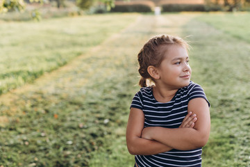 Outdoor portrait of young girl explores the outside world in summer park. Childhood, positive emotions, summer concept