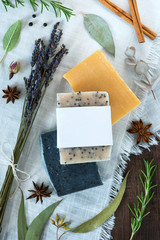 three bars of soap on a white cloth with natural ingredients, handmade soap with blank label, mockup label flat lay, rosemary, eucalyptus, star anise, lavender, peppercorns, cinnamon, rosebud, sage