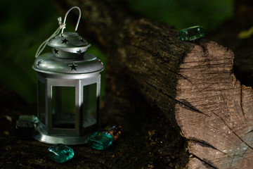 Silver lamp with three glass color stones on a log near a lake