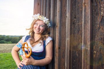 Young woman with pretzel on a wood background .Oktoberfest concept