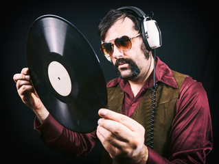 Man wearing authentic vintage 1970's era clothing, including a vest, sunglasses and long collared...