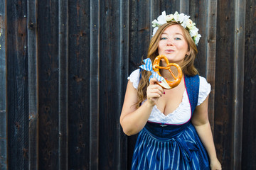 Young woman with pretzel on a wood background .Oktoberfest concept