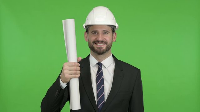 Cheerful Engineer showing Construction Blueprint against Chroma Key