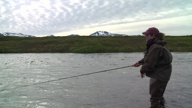 Male fly angler casting in American Creek for trout