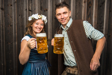 Junge Frau und mann mit Bierkrug und Brezel auf einem Holzhintergrund .Oktoberfest-Konzept 